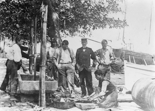 Μια παρέα αντρών στην παραλία ανάμεσα στις βάρκες